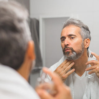 Man in the bathroom using cologne